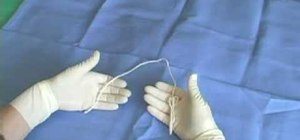 Perform a two handed suture tie on an animal